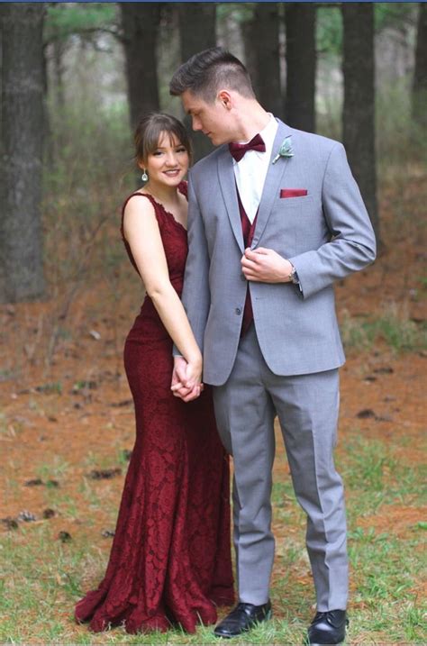 a man and woman in formal wear standing next to each other holding hands with trees in the