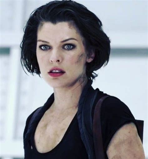 A Woman With Dark Hair And Blue Eyes Wearing A Black Top Is Looking At