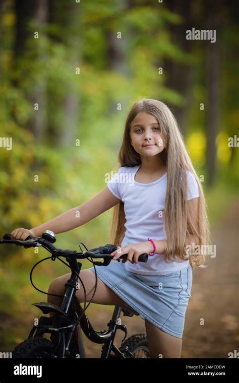 Cute Little Teenager Girl Riding Bicycle In A Sunny Park Stock Photo