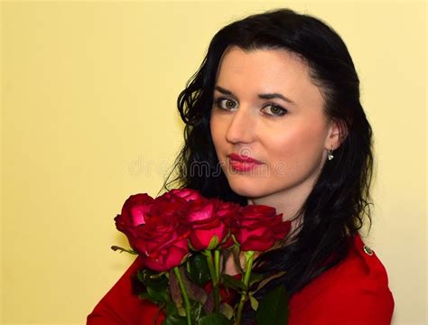 The Young Woman The Brunette In A Red Dress With Red Roses Stock Photo
