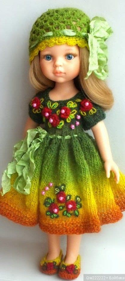 a doll wearing a green and yellow dress with red flowers on it s head
