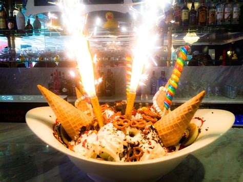 An Ice Cream Sundae With Three Cones On Top And Lit Candles In The Middle
