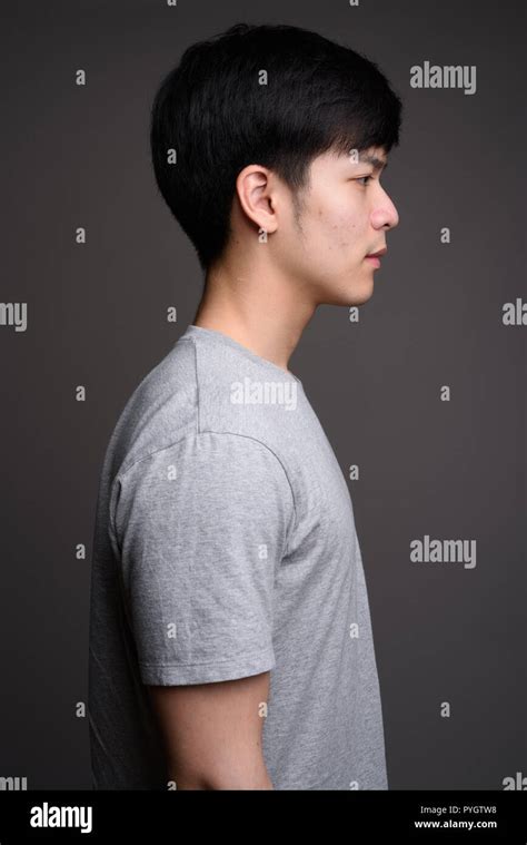Profile View Of Young Handsome Asian Man Against Gray Background Stock