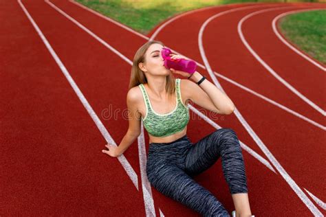Athletic Girl Sitting On The Stadium Track And Drinking Water From A Bottle Stock Image Image