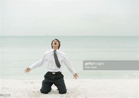 Businessman Down On Knees Screaming On Beach Photo Getty Images