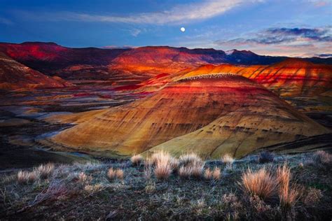 The Hills Are Painted In Different Colors And Shapes At Sunset With A