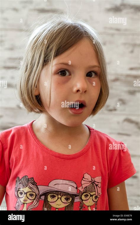 Surprised Little Girl In Front Of White Wooden Background Stock Photo