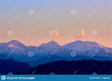 Three Clouds Over Mountain Peaks In The Rays Of Sunset Stock Image