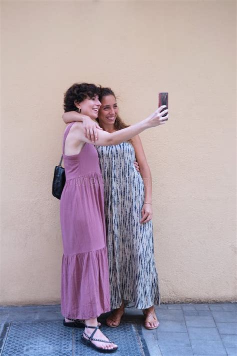 hermosa pareja de lesbianas con vestidos largos hablando y cogiendo de la mano en la calle