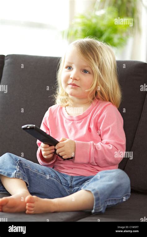 Young Girl Watching Tv Alone In The Living Room Holding A Remote