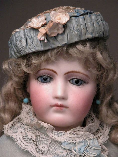 A Close Up Of A Doll Wearing A Hat With Flowers On Its Head