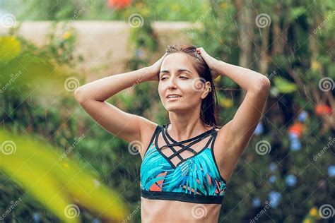 A Tanned Slender Woman In A Swimsuit Posing In The Refreshing Tropical Rain Smoothing Her