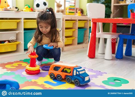 Adorable Hispanic Girl Playing With Hoops Toys Sitting On Floor At