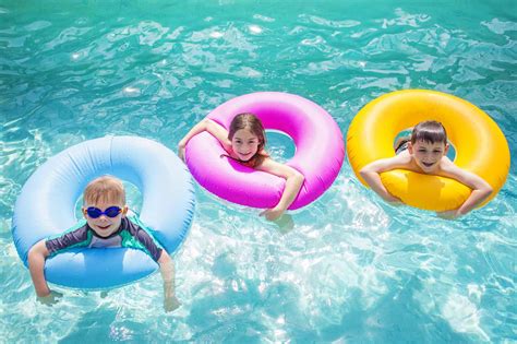 Group Of Kids Playing On Inflatable Tubes In Swimming Pool