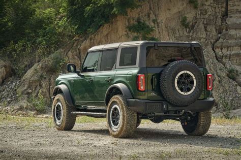 A Green Jeep Is Parked In Front Of A Cliff