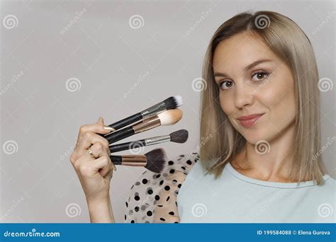 Mulher Loira Segurando Pincel De Maquiagem E Posando Contra Fundo Cinza Foto De Stock Imagem