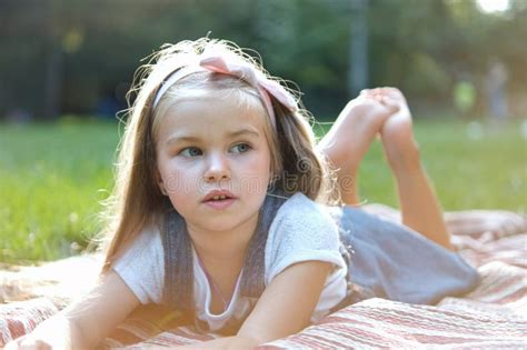 Portrait Of Pretty Child Girl Resting Outdoors In Summer Park Stock