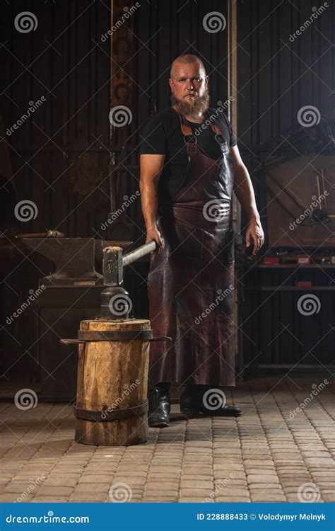 Full Ength Portrait Of Bearded Man Blacksmith Working On Creating