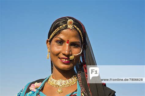 lächelnde junge inderin mit kopftuch und schmuck porträt