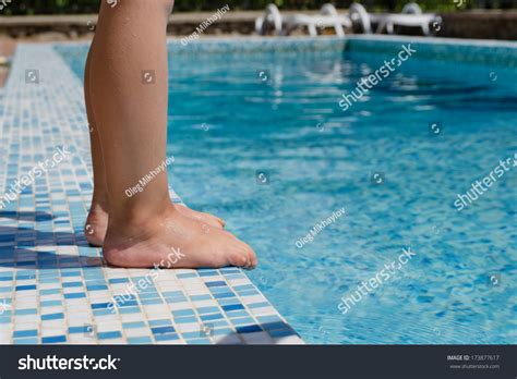 Young Child Standing Barefoot At The Edge Of A Swimming Pool Just Above