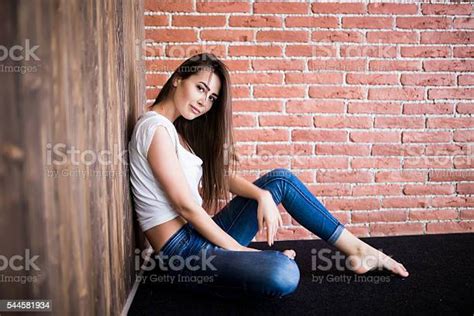 Girl Sitting Down Against Wooden And Brick Wall Stock Photo Download