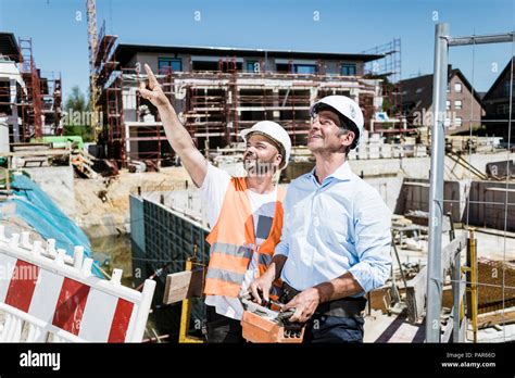 Smiling Construction Worker Talking To Man On Construction Site Stock