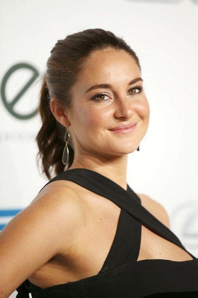 A Woman In A Black Dress Smiling At The Camera With Her Hair Pulled