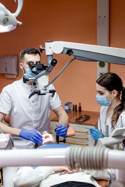 Premium Photo Dentist With Assistant Under Microscope Treats The