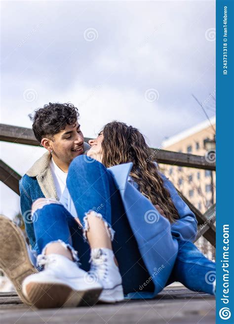 Young Interracial Smiling Young Couple Sitting On The Street Looking At Each Other About To Kiss
