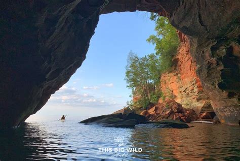 A Person Paddling In A Kayak Out Into The Ocean From Inside A Cave
