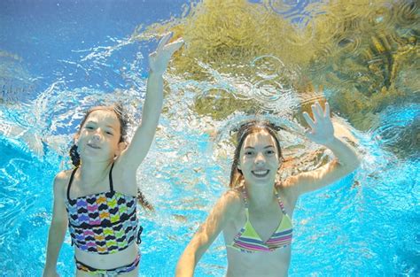 Children Swim Underwater In Swimming Pool Happy Active Girls Have Fun