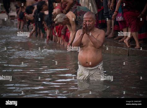 A Nepalese Devotee Takes A Holy Bath In The River While Praying During