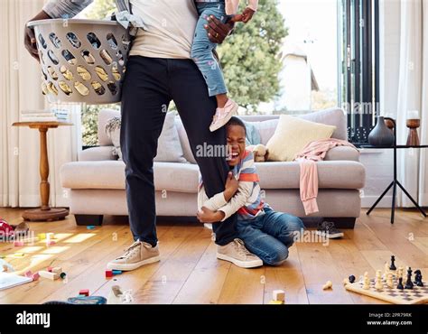 A Little Boy Throwing A Tantrum While Holding His Parents Leg At Home