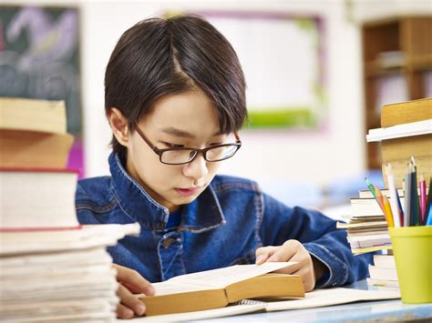 Asian Schoolboy Reading Book In Classroom Review Of Myopia Management