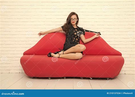 Portrait Of A Beautiful Sensual Woman Relaxed Girl Sitting On Red Sofa Model On Leather Couch
