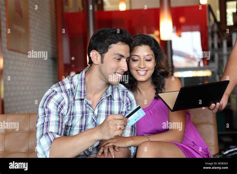 Indian Young Couple Paying Bill By Credit Card In A Restaurant Stock