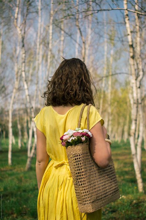Anonymous Woman In Yellow Dress Holding A Bag With Flowers By Stocksy