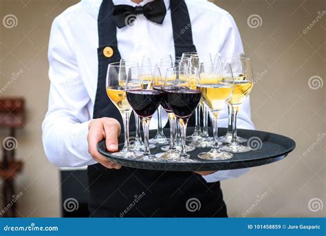 Professional Waiter In Black Uniform Serving Red And White Wine Stock