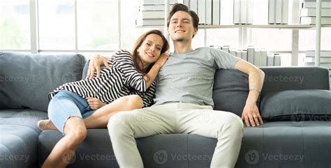 una pareja romántica y afectuosa abrazándose sentada en un sofá