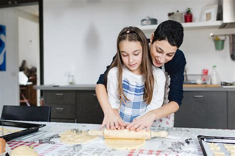 Mother And Daughter Stretch The Dough With A Rolling Pin Together Del Colaborador De Stocksy