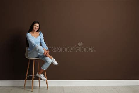 Piękna Młoda Kobieta Siedząca Na Stołku Przy Brązowej ścianie Spacja Dla Tekstu Obraz Stock