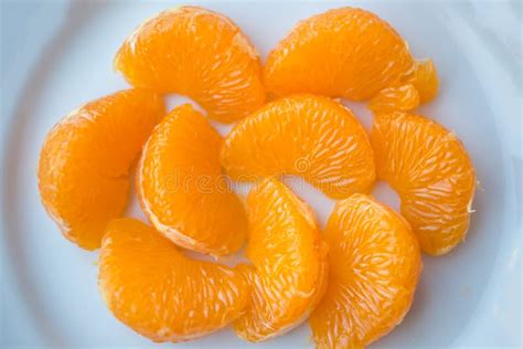 Fresh Peeled Orange Mandarin Pieces On White Plate Top View