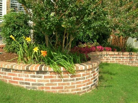 A Brick Garden Wall With Flowers And Trees In The Background