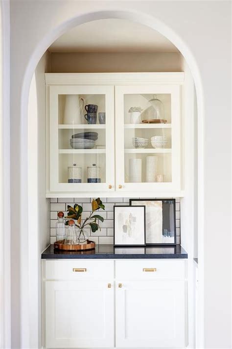 The white shaker collection offers a beautiful, sophisticated look to any style kitchen. White shaker butler's pantry cabinets are accented with brass hardware and a black quartz ...