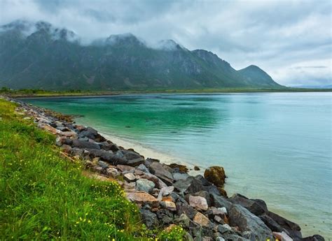 Lofoten 피요르드와 호수는 모래 해변 호수 산 노르웨이이있는 흐린 풍경입니다 여름 극지 낮 야경 프리미엄 사진