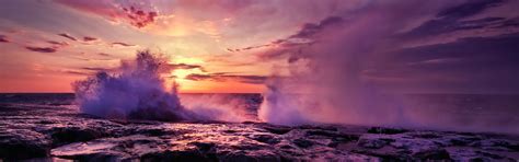 The Sun Is Setting Over An Ocean With Waves Crashing On Rocks And Foamy
