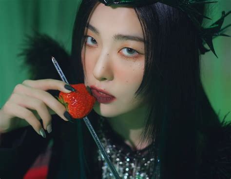 A Woman With Long Black Hair Holding A Strawberries In Her Mouth