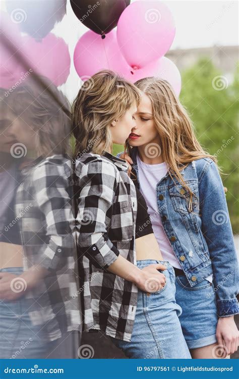 Casual Lesbian Couple Kissing And Holding Air Balloons Outdoors Stock