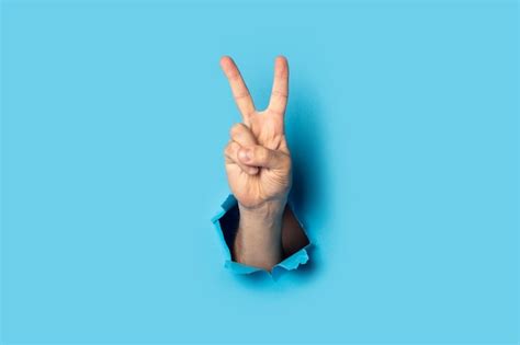 Premium Photo Male Hand Makes A Two Fingers Up Greeting Gesture On Blue