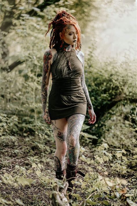 A Woman With Red Hair And Tattoos Walking Through The Woods In Her